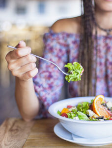 Young woman eating salad in restaurant, alone.