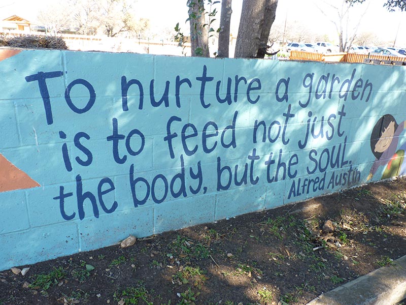 mural with smiling child on the right. Scripted handwriting reads: to nurture a garden is to feed not just the body, but the soul. Attributed to alfred austin