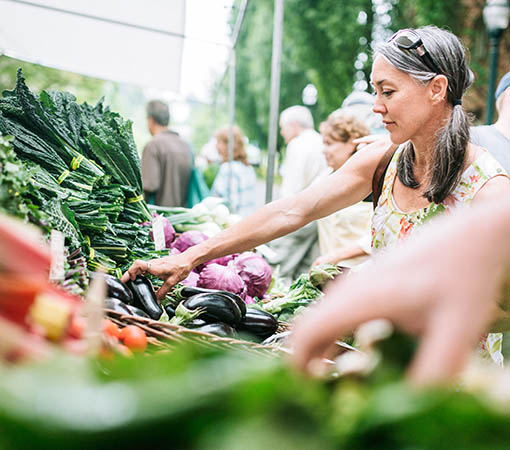 Woman at market grabbing fresh vegetables